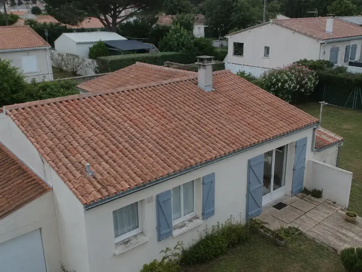Vue de drone d'un pavillon aux volets bleus avec une toiture en tuiles mécaniques neuves